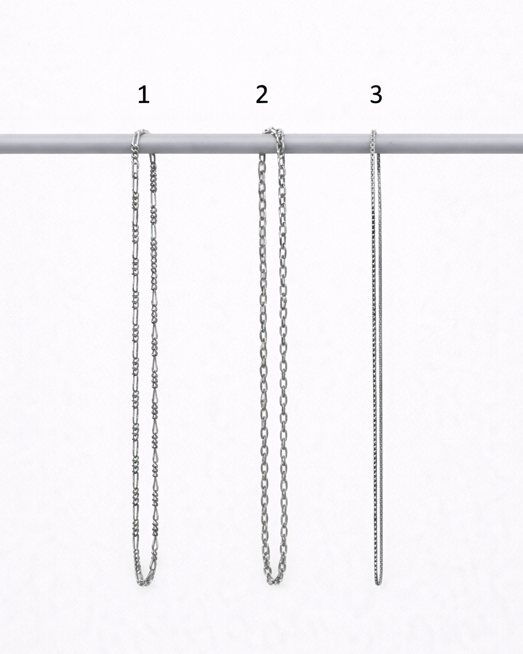 Three silver chain necklaces of different lengths on a white background