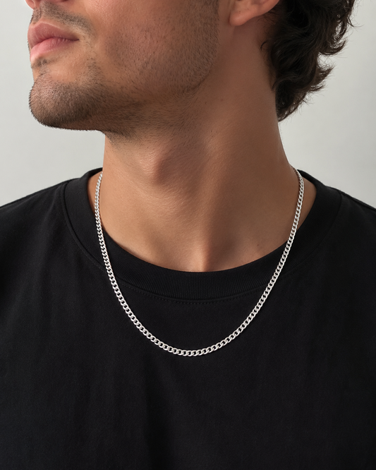 Man wearing a silver chain necklace against a neutral background