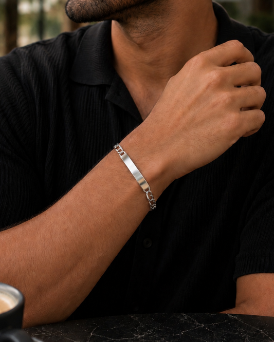 Man wearing a silver bracelet sitting at a table with a cup of coffee.