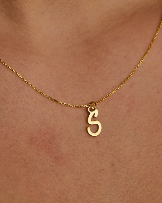 Gold necklace with a unique pendant on a person's neck