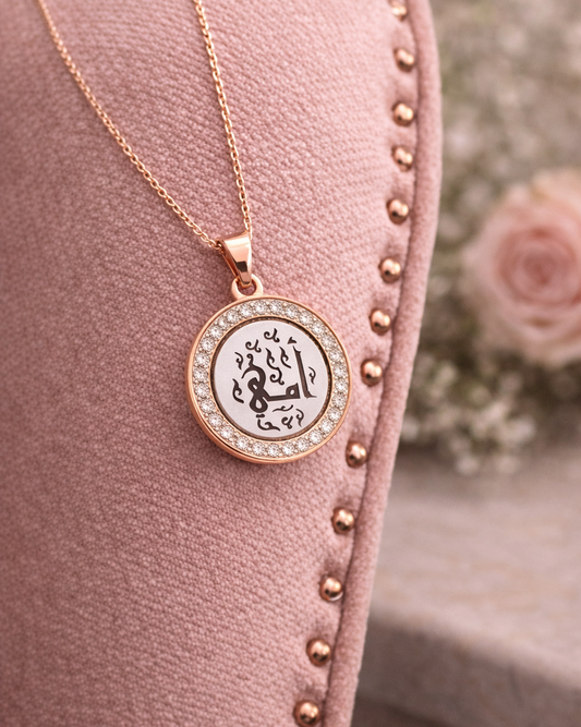 Rose gold necklace with a round pendant on a pink cushion with floral background