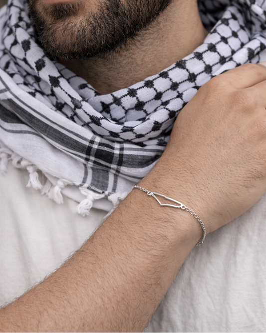 Man wearing a black and white checkered scarf with a silver bracelet on his wrist.