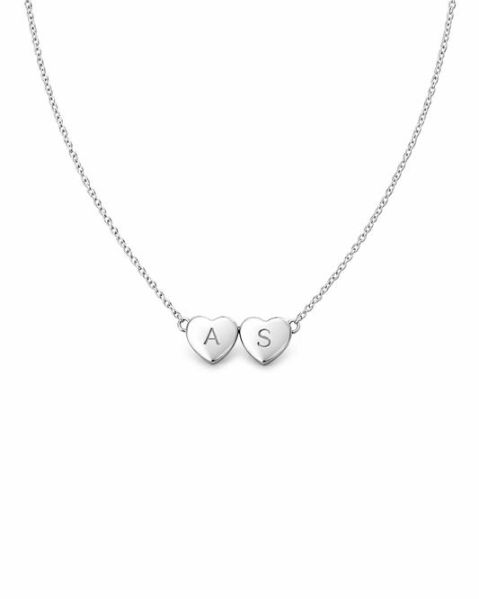 Silver necklace with two heart-shaped pendants on a white background