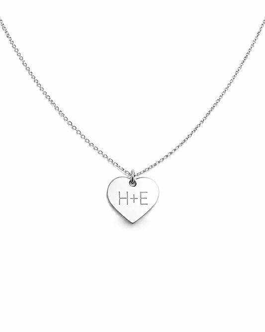 Silver heart-shaped necklace with 'H+E' engraving on a white background