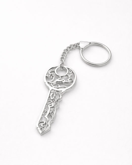 Silver key-shaped keychain with intricate design on a white background