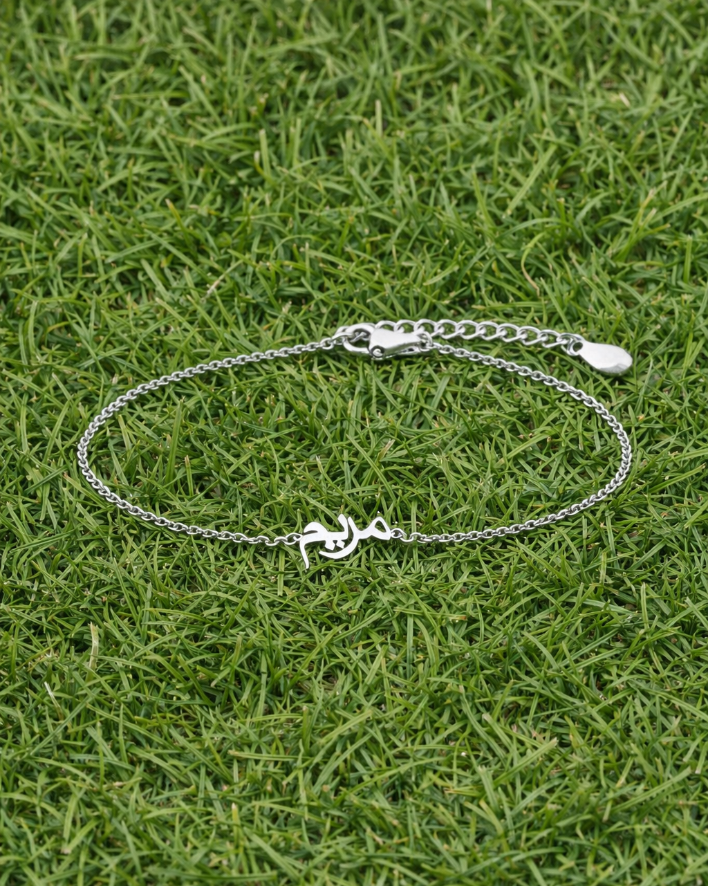 Silver bracelet with a anchor charm on grass