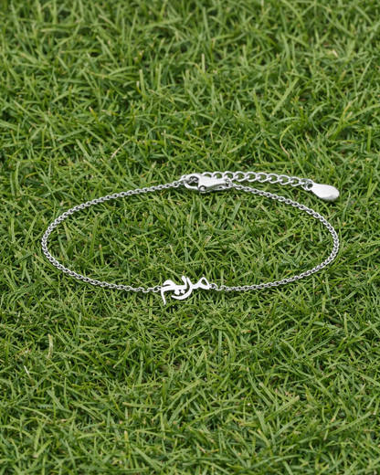 Silver bracelet with a anchor charm on grass