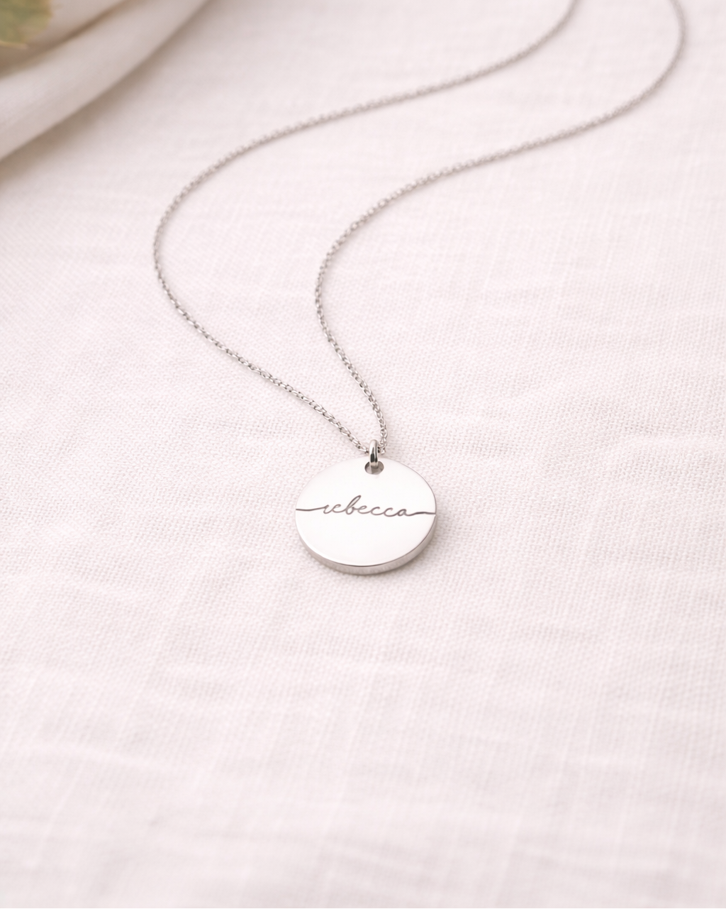 Silver necklace with a round pendant on a light background