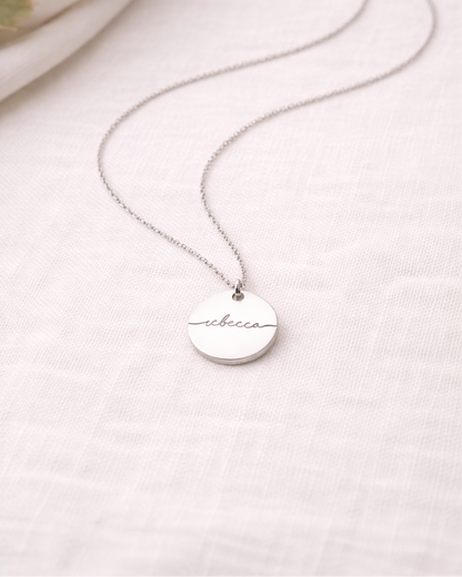 Silver necklace with a round pendant on a light background