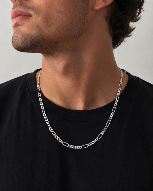 Man wearing a silver chain necklace against a neutral background