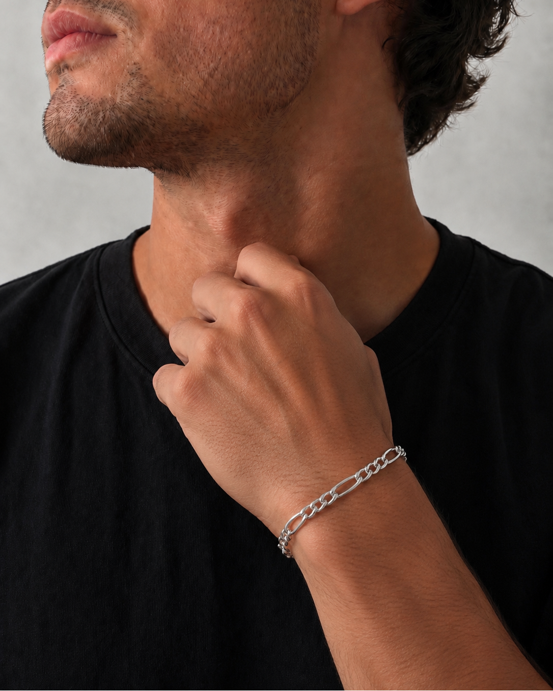 Man wearing a silver chain bracelet on a plain background