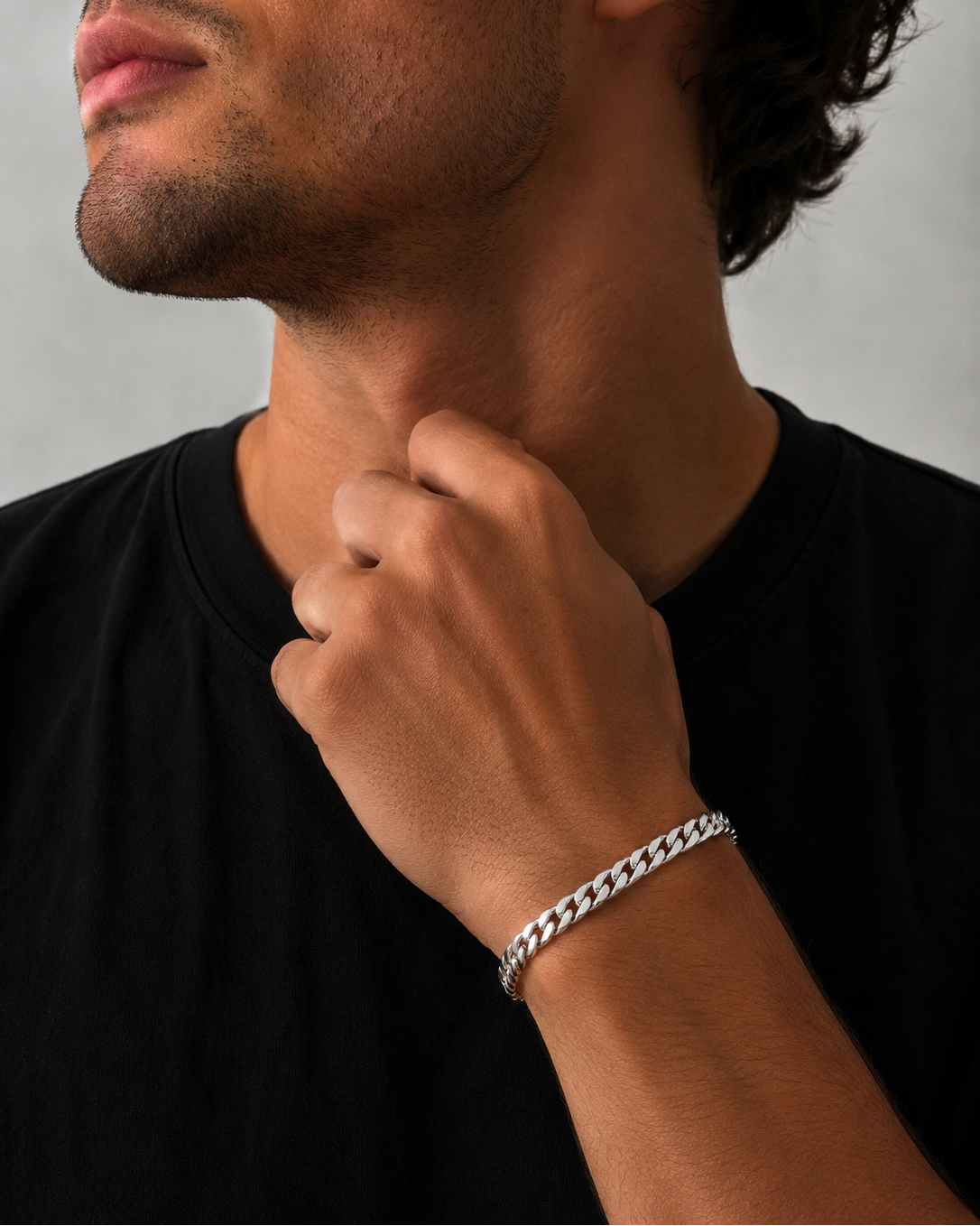 Man wearing a silver chain bracelet on his wrist against a neutral background