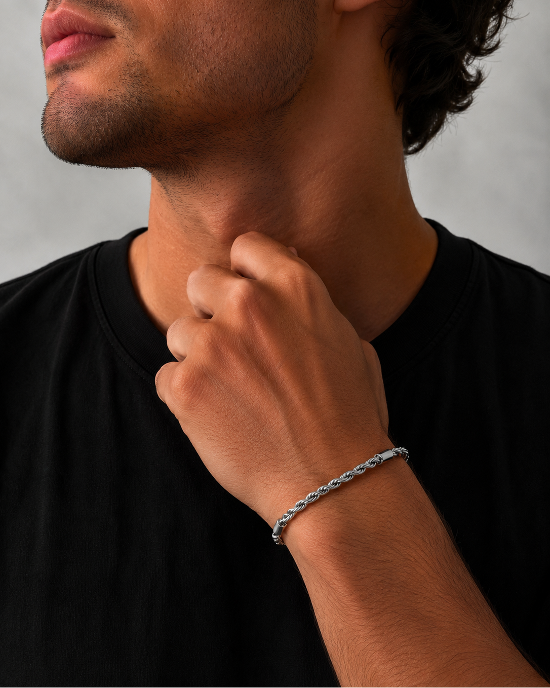 Man wearing a silver bracelet on his wrist with a neutral background