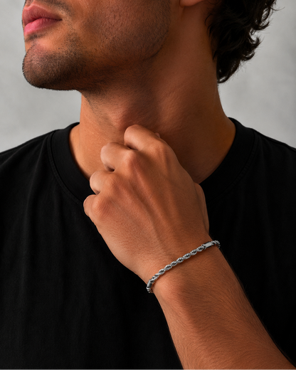 Man wearing a silver bracelet on his wrist with a neutral background