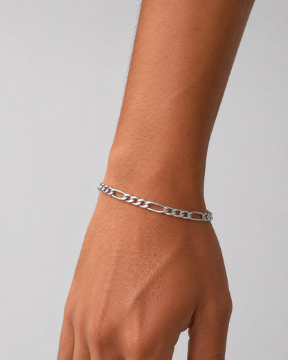 Silver chain bracelet on a wrist against a neutral background