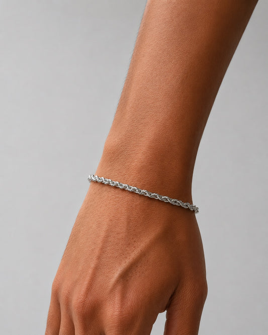 Silver bracelet on a wrist against a gray background