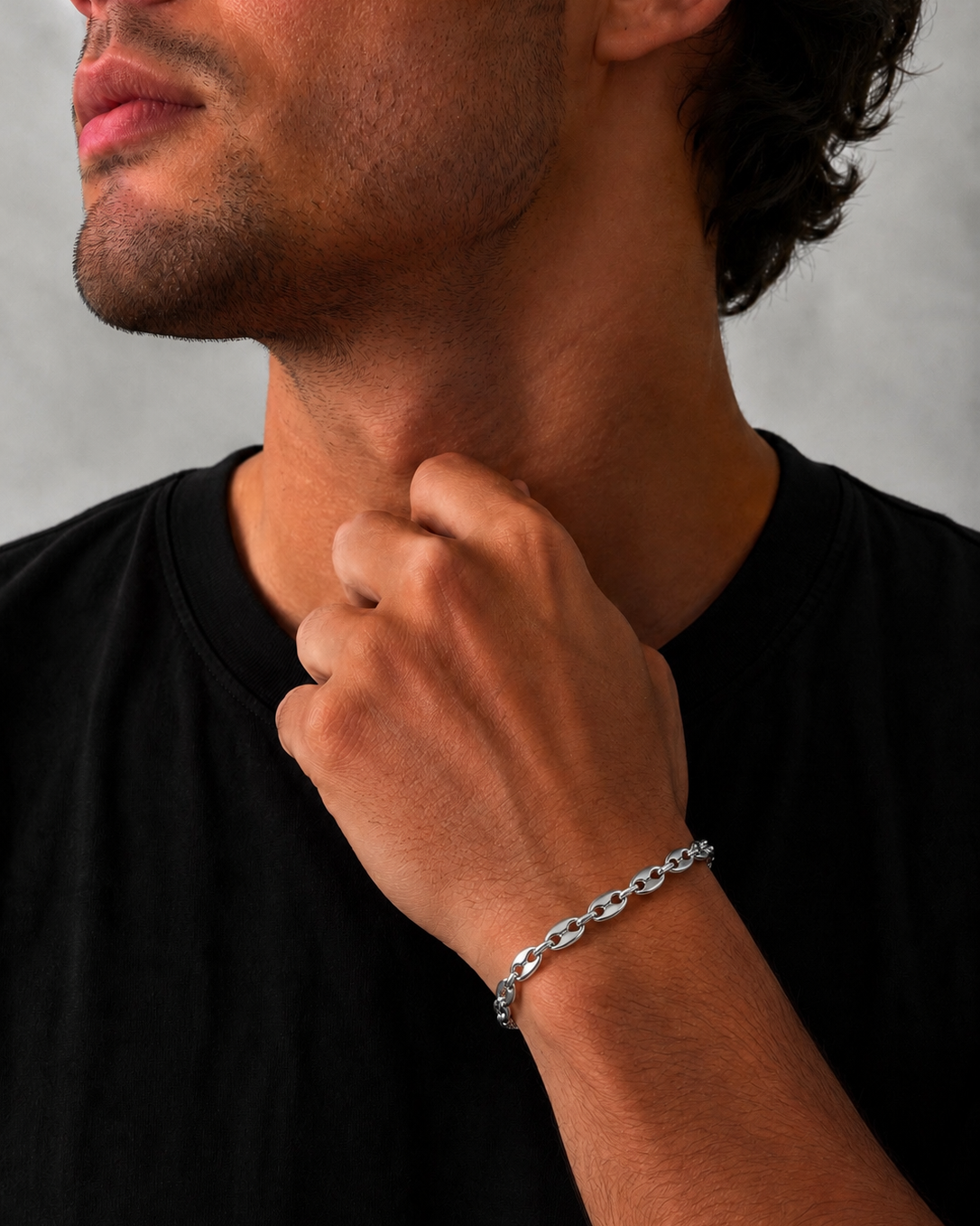 Man wearing a silver bracelet on his wrist with a neutral background