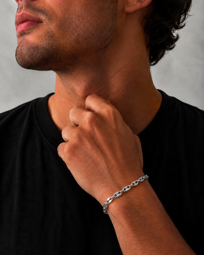 Man wearing a silver bracelet on his wrist with a neutral background