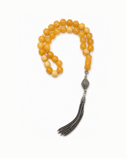 Yellow beaded necklace with a silver tassel on a white background