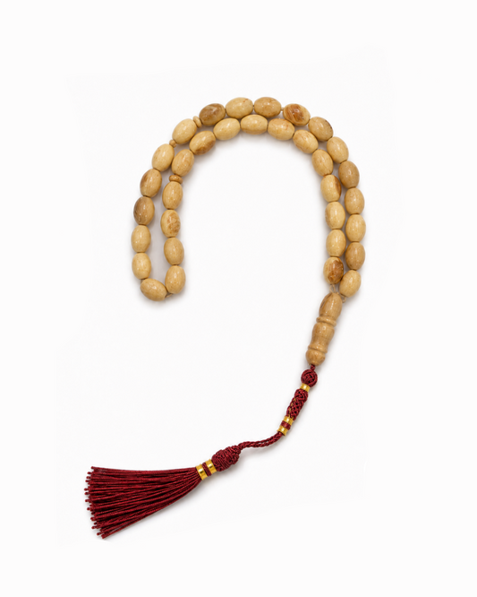 Wooden prayer beads with a red tassel on a white background