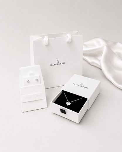 Jewelry set including earrings and a necklace in 'Silver Corner' packaging on a white background