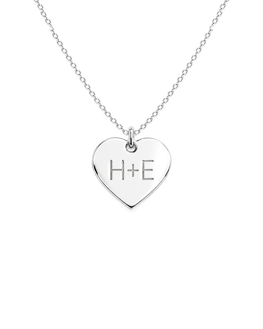 Silver heart-shaped necklace with 'H+E' engraving on a white background