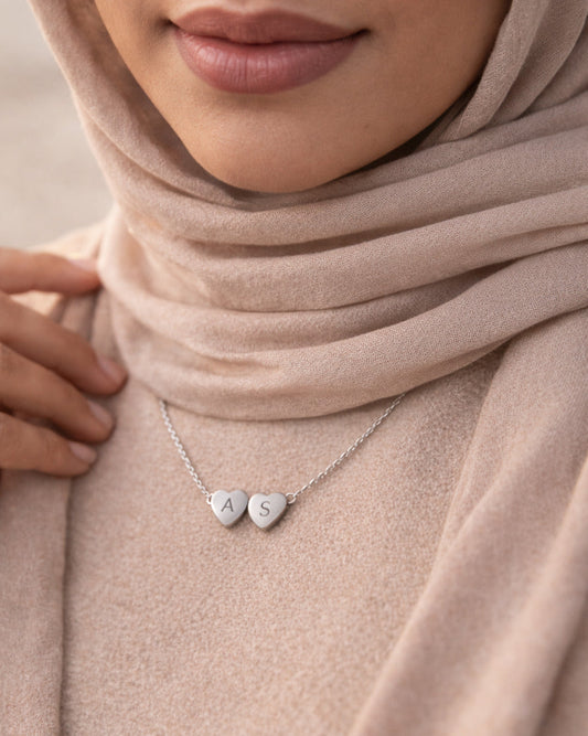 Close-up of a person wearing a hijab with a necklace featuring heart-shaped pendants.