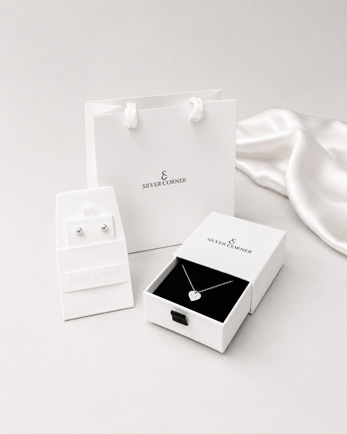 Jewelry set including earrings and a necklace in 'Silver Corner' packaging on a white background