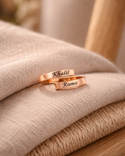 Rose gold ring with engraved names on a textured surface